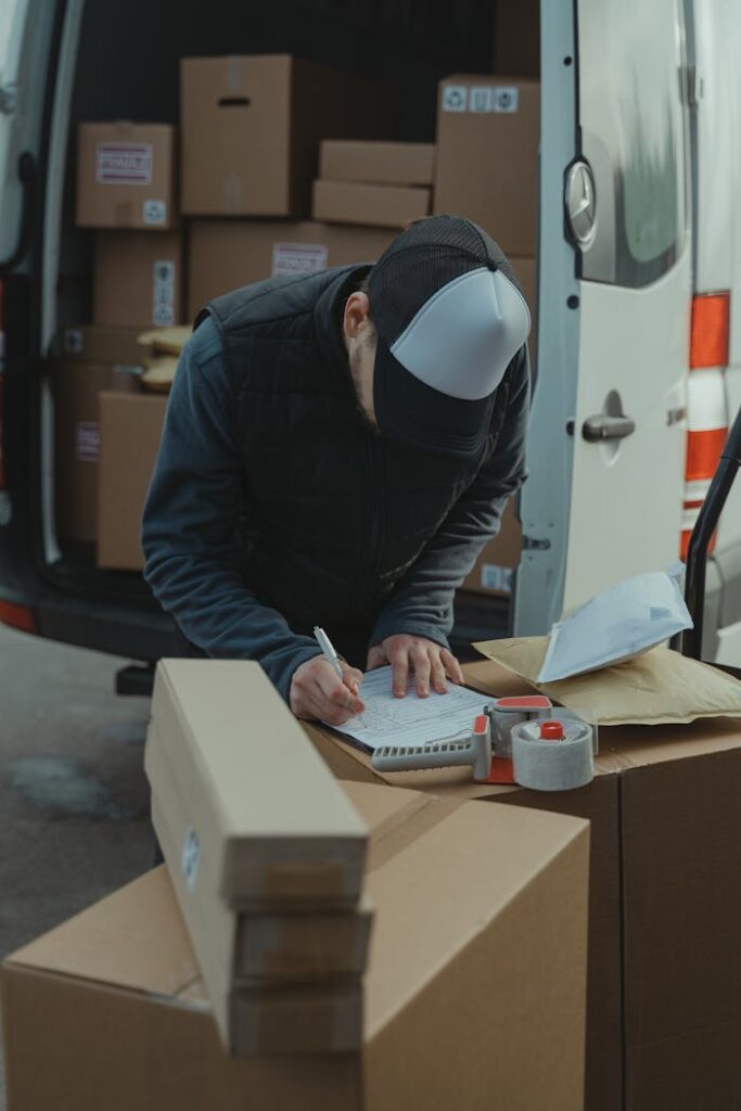 pexels photo 6169057 Courier organizing packages from a van, preparing for delivery in a logistics setting.